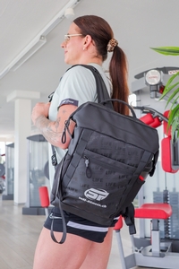 Eine Sportlerin trägt den self-fitness.ch Rucksack im Fitnessstudio.