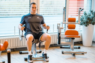 Sportler gym80 Circular Training an der Bizeps- und Trizepsmaschine