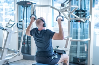 Nahaufnahme eines Sportlers an der Latzugmaschine von Schnell