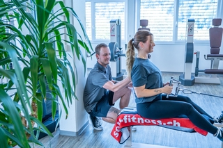 Trainer beim instruieren des engen Rudern am Kabelzug mit Kundin