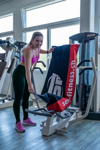 Eine Kundin platziert ihr self-fitness.ch Trainingshandtuch auf einem Schnellkraftgerät während des Workouts im Fitnessstudio.