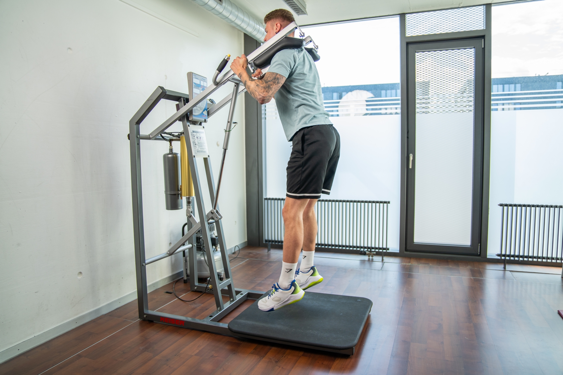 Ein Sportler führt Kniebeugen an einem Keiser Air Squat aus.