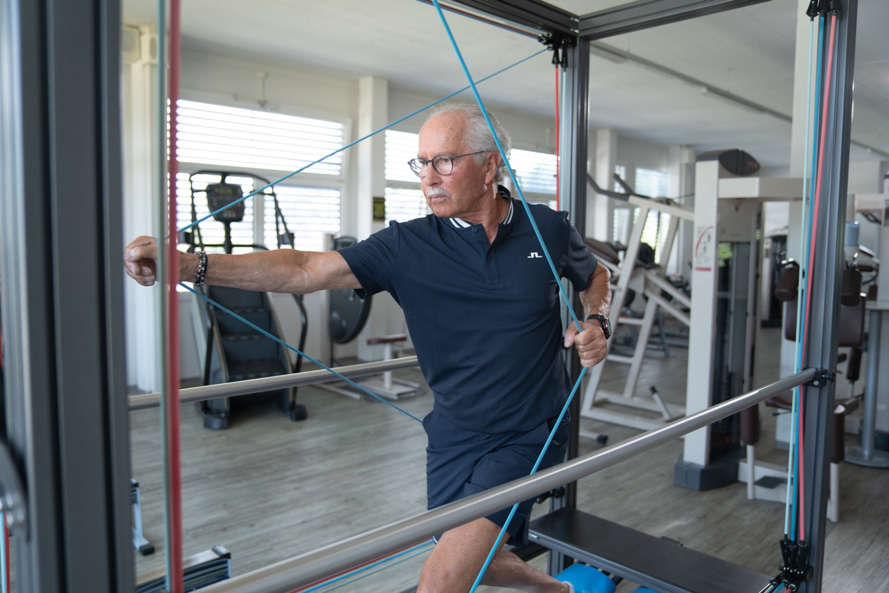 Trainer beim instruieren eines Sportlers auf dem Crosstrainer