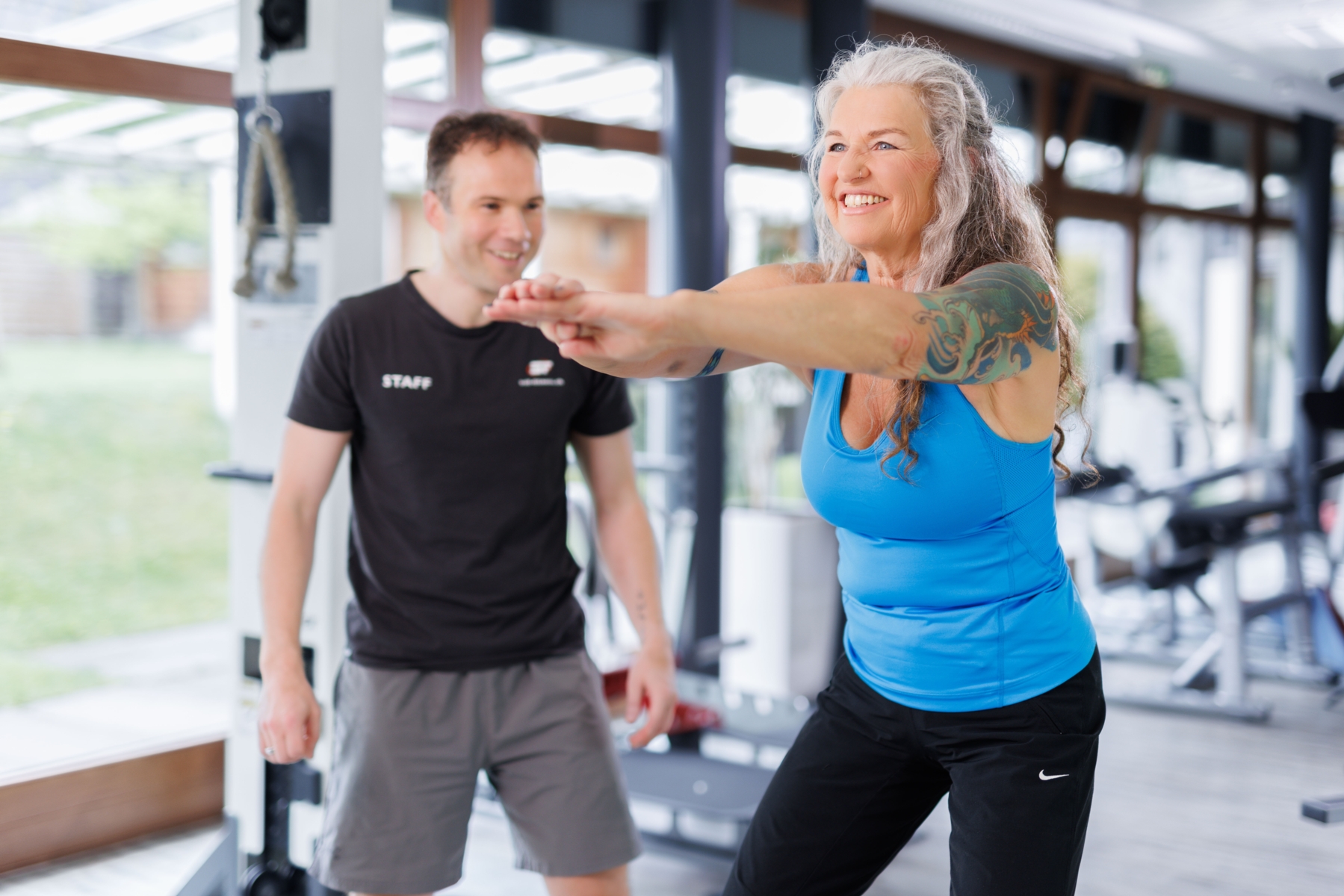 Trainer beim instruieren eines Sportlers auf dem Crosstrainer