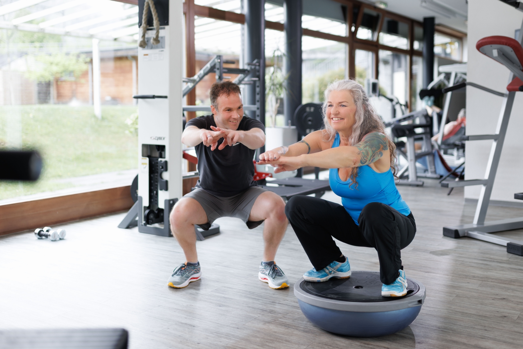 Trainer beim instruieren eines Sportlers auf dem Crosstrainer