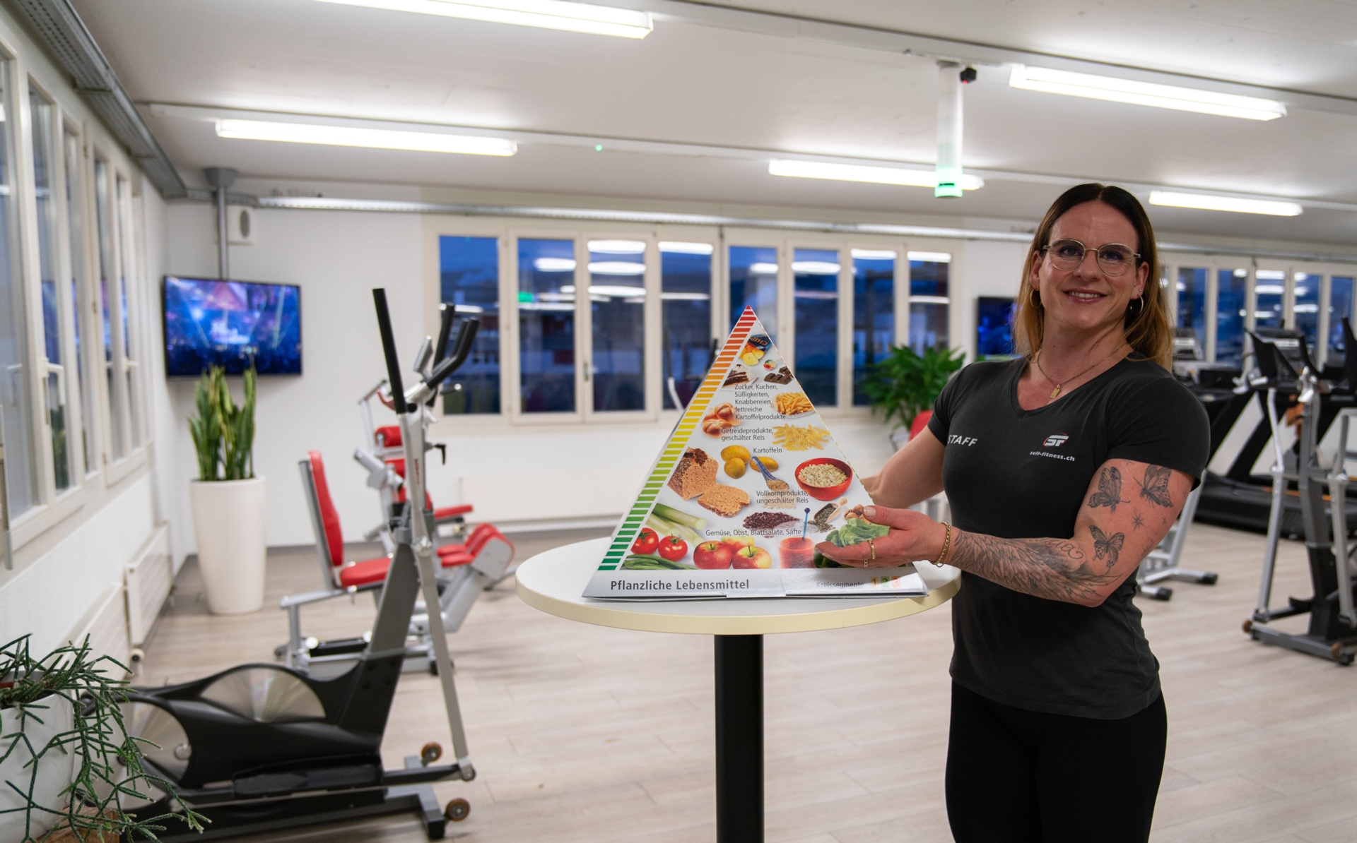 Trainerin zeigt an einer 3D Lebensmittelpyramide auf die Stufe Gemüse.